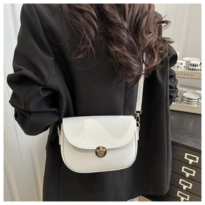 Close-up of white lychee leather saddle bag with round golden metal buckle on model