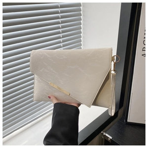 Detail of cream envelope bag featuring gold metal bar and textured marble finish