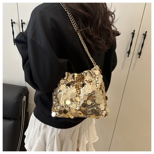 Golden sequin crossbody bag with delicate metal chain strap shown on model shoulder