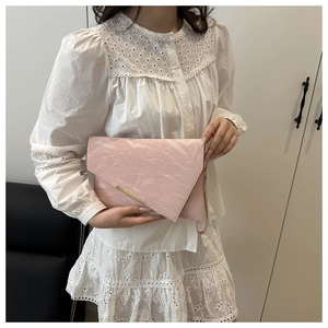 Close-up of pink envelope bag showing wrinkled texture and gold metal buckle detail