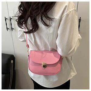 Detailed shot of pink pebble texture saddle bag with golden circular metal buckle