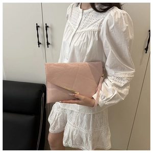 Detail of pink envelope clutch bag with gold metal trim and leather wrist strap