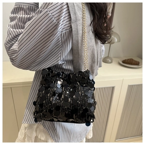 Close-up of sparkling black sequins and gold chain strap on a stylish crossbody bag