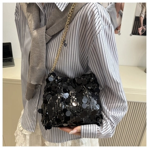 Close-up of black sequin evening bag with gold chain strap on a model shoulder