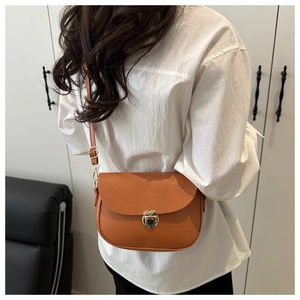 Detail of orange-brown saddle bag with lychee grain leather and golden metal buckle