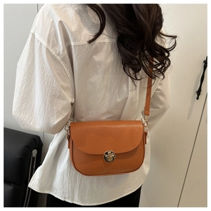 Close-up of tan lychee grain leather saddle bag with vintage gold metal buckle