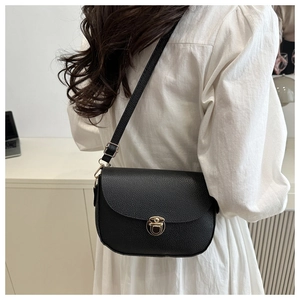Close-up of black lychee grain saddle bag with gold metal buckle on model shoulder