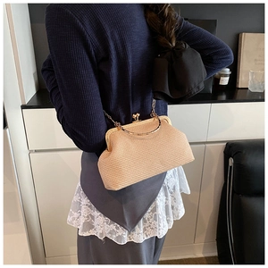 Détail d'un sac coquillage tissé beige avec poignée dorée ronde et bandoulière chaîne