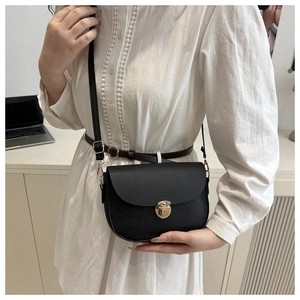 Detail of black pebbled leather saddle bag featuring a round gold-tone metal buckle