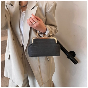Détail d'un sac à main noir tressé avec poignée dorée et bandoulière chaîne sur mannequin