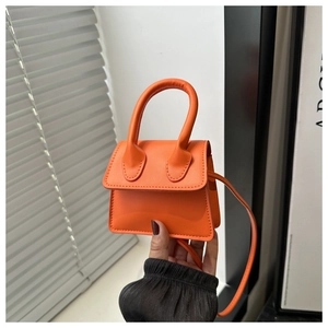 Detailed close-up of an orange leather mini handbag with top handle and fine stitching