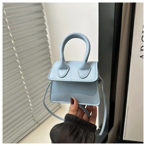 Close-up of light blue mini handbag with top handle and matching crossbody strap