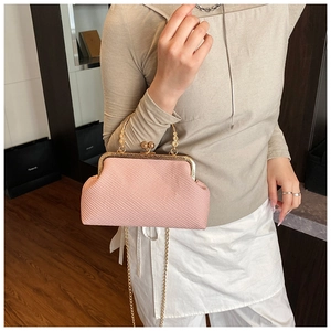 Détail d'un sac tissé rose avec fermoir doré rétro et poignées métalliques sculptées