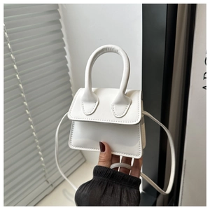 Close-up of a white leather mini handbag showing top handle and fine stitching detail