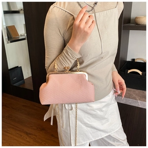 Détail du sac coquillage rose tissé avec fermoir doré et bandoulière en chaîne