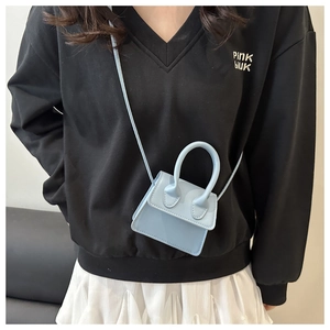 Sky blue mini leather crossbody bag with top handle worn on casual outfit