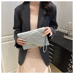 Silver clutch bag featuring unique pleated texture and elegant gold metallic bar detail