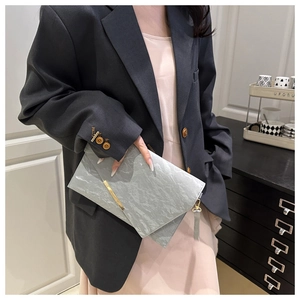 Detail of light gray marble envelope clutch with elegant gold metal bar and wrist strap