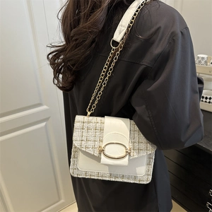 Sac bandoulière en tweed crème avec chaîne dorée porté par un mannequin de côté