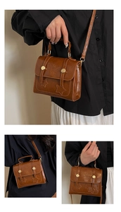 Detail of vintage brown leather bag showing star stitching and metal buckle accents