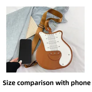 Guitar shaped crossbody bag in brown and white PU leather next to a smartphone