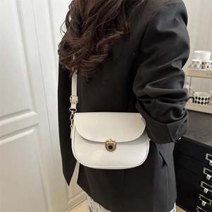 White lychee pattern saddle bag with gold buckle on a model wearing a black blazer