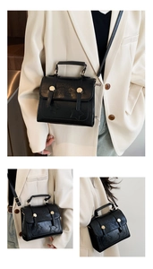 Detail of black matte leather messenger bag with star embossing and gold metal buckle