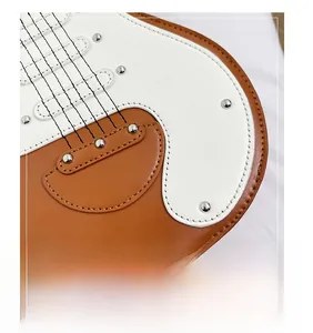 Detail of guitar-shaped bag showing caramel leather stitching and silver metal rivets