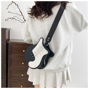 Detail of the electric guitar-shaped crossbody bag with wide strap on a female model