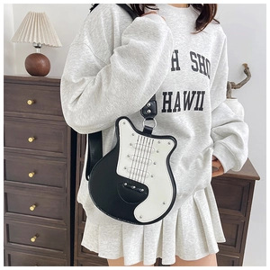 Close-up of guitar-shaped crossbody bag with rivet details and black and white contrast