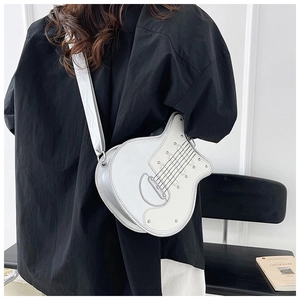 Close-up of silver guitar-shaped crossbody bag with metallic studs on a black outfit