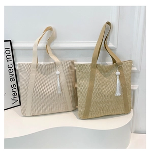 Detail view of woven straw tote bags in beige and khaki with soft decorative tassels
