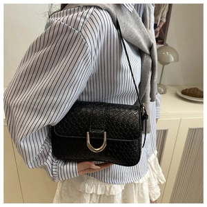 Detail of retro black woven texture shoulder bag with large gold U-shaped metal buckle