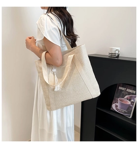 Detail view of large woven tote bag with fringe tassel and wide shoulder strap