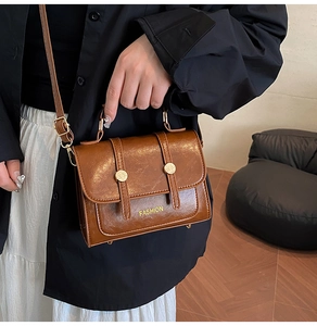 Detail of brown vintage oil wax leather handbag with gold buckles and fashion logo
