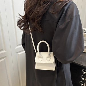 Minimalist white mini crossbody bag shown on model highlighting compact fashion style