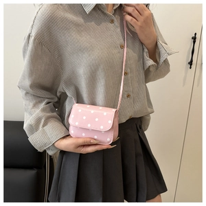 Mini sac à bandoulière rose à pois blancs porté par un mannequin en tenue décontractée