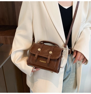 Close-up of a brown oil wax leather mini handbag worn with a white blazer
