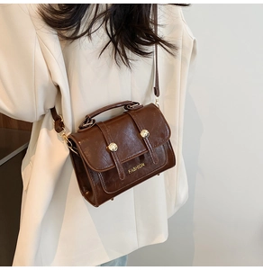 Detail of vintage brown leather handbag with gold buckles and adjustable shoulder strap