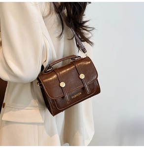 Detail of vintage brown crossbody bag with gold hardware and smooth oil-wax texture