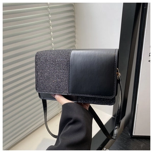 Detail of a black patchwork flap bag with shiny glitter finish and matte leather texture
