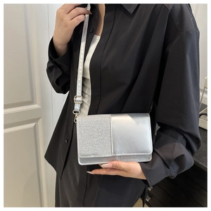 Detail of silver crossbody bag featuring glitter fabric and smooth leather contrast