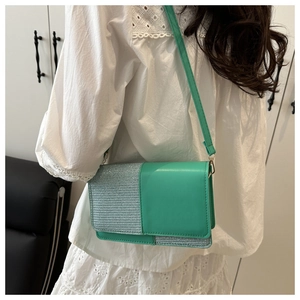 Detail of mint green leather crossbody bag with silver sequins on white lace top