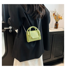Detailed view of lime green crocodile texture mini handbag with silver chain strap