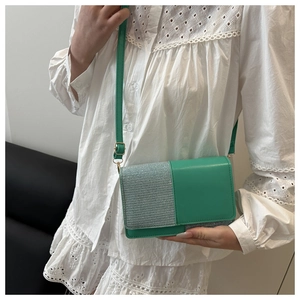 Detail of green contrast crossbody bag with sequin fabric texture on a white shirt