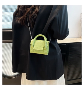 Detail of neon green mini crossbody bag with crocodile texture on a model outfit