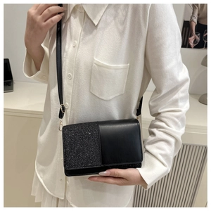 Detail of a black crossbody bag showing dual texture glitter and smooth leather finish