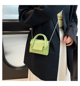 Detail of bright green crocodile embossed mini bag with silver chain strap and top handle