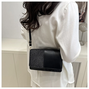 Detail of a chic black sequin and leather crossbody bag with a slim strap and gold buckle