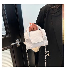 Detail of white crocodile embossed texture on a mini crossbody bag with silver chain
